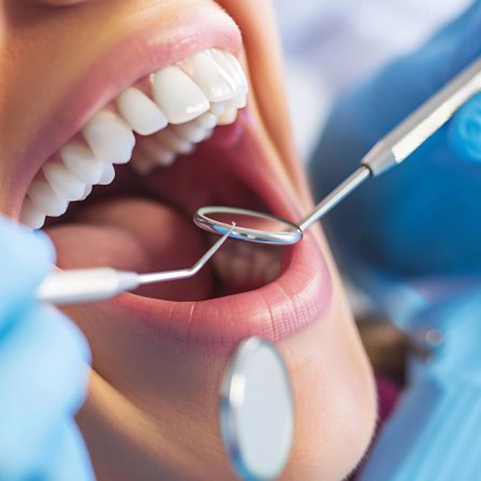 a patient getting their teeth checked with a dental mirror