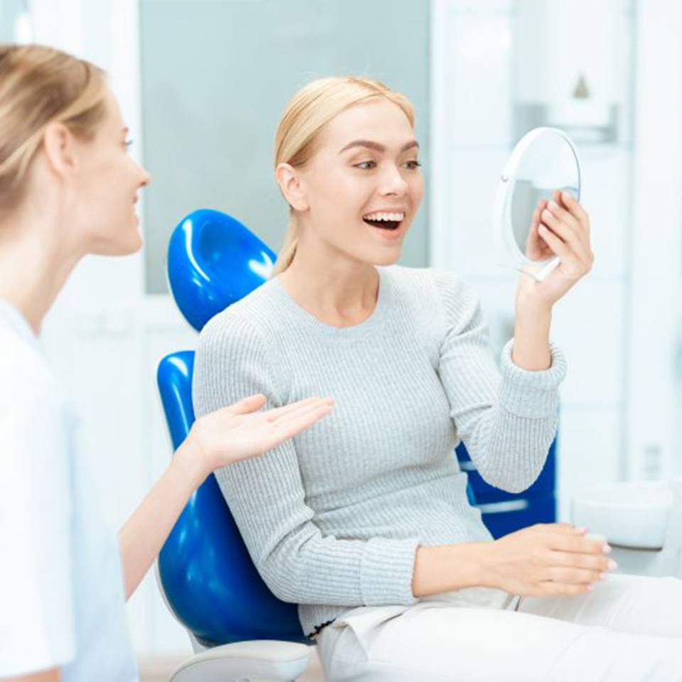 a patient checking her smile with a mirror