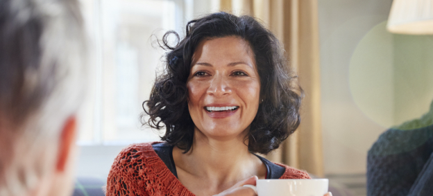 Smiling woman in red sweater holding white coffee cup
