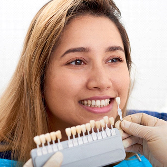 A dentist in St. Johns using a shade guide to determine the color of the patient’s veneers