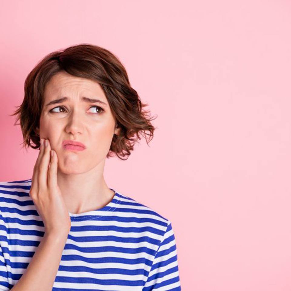 Woman rubbing her jaw because her wisdom teeth hurt