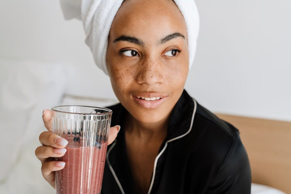 A woman drinking a smoothie in her pajamas.